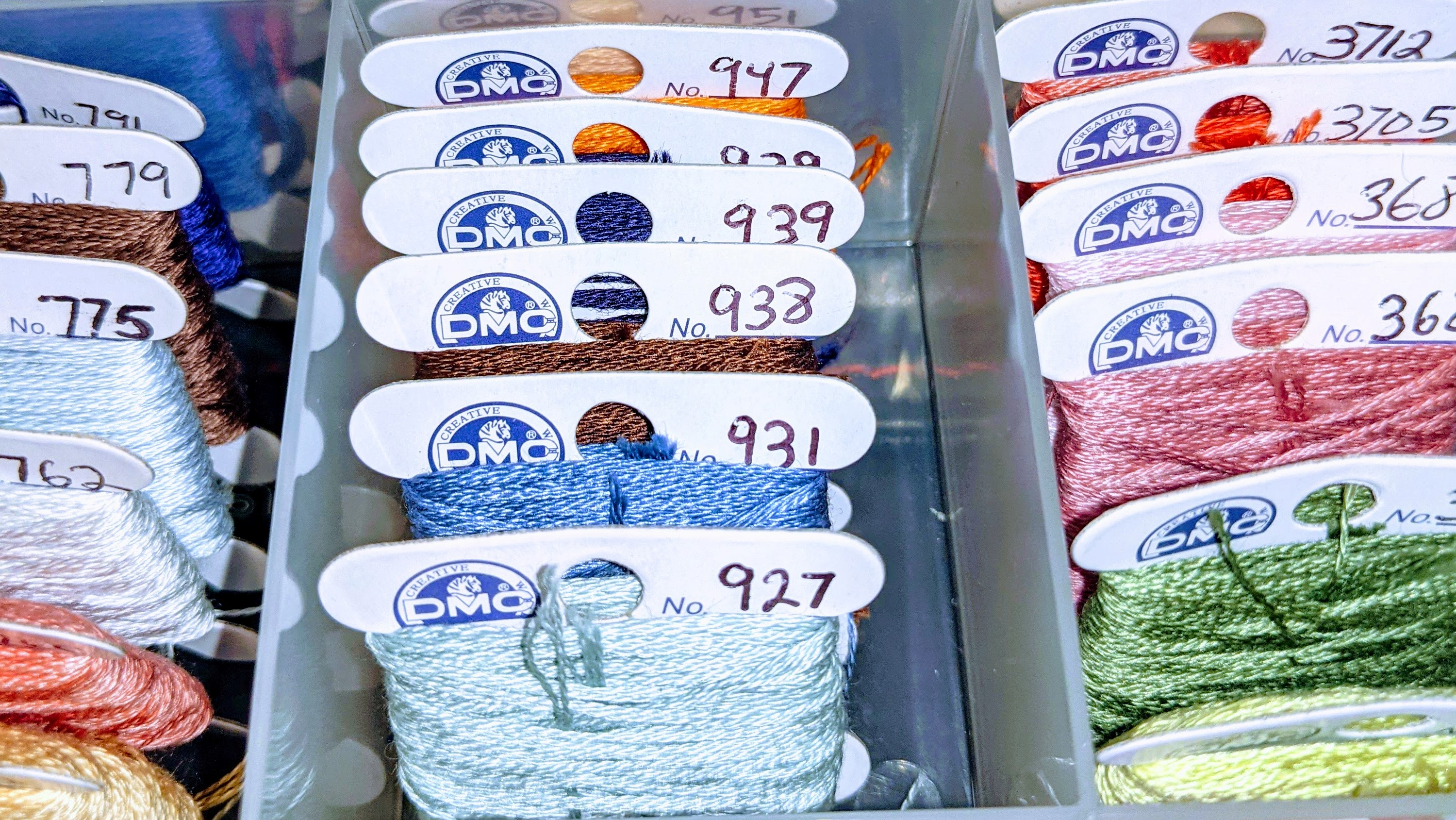 A close up of a box full of bobbined cross-stitching floss