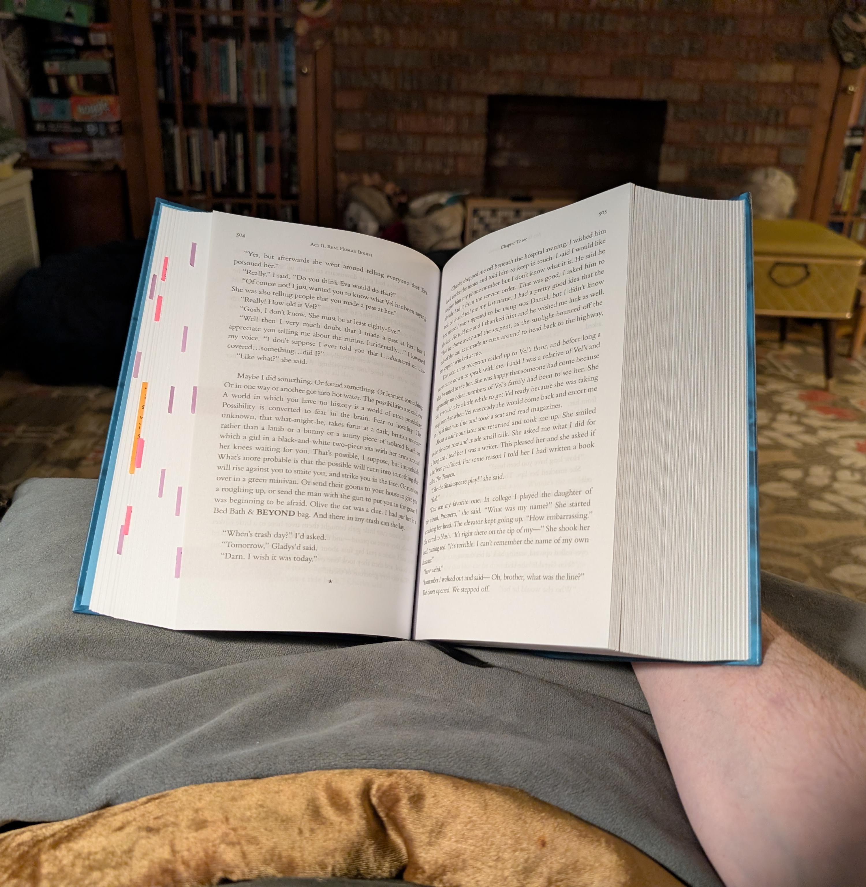 Book open and resting on a pillow, with its spin propped by my hand